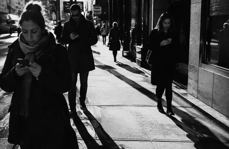 People passing each other on a sidewalk, all absorbed in their phones